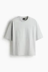 Remera de algodón pesado color gris melange, con cuello redondo ribeteado, hombros caídos y corte oversized.