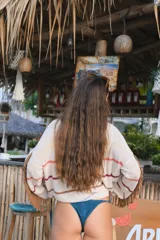 Buzo con capucha de tejido de punto abierto, color blanco roto, de corte oversize y manga larga con detalle de flecos en los puños.