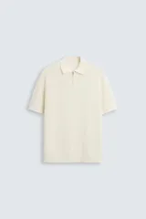 Polo de manga corta, color azul medio, tejido en punto perlado con cuello solapa y cierre frontal de cremallera.