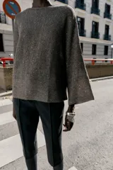 Jersey de punto color marrón oscuro con lentejuelas plateadas, cuello barco y manga larga acampanada.