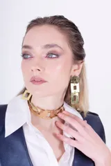 Gargantilla rígida dorada con diseño de cuadrados calados.