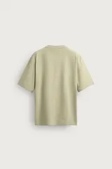 Camiseta boxy fit color verde militar con efecto lavado, confeccionada en tejido compacto de algodón, con cuello redondo y manga corta.