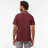Remera polo de piqué color bordó con cuello y mangas con ribete blanco.