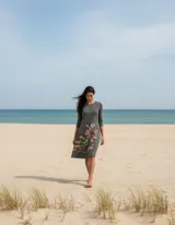 Vestido midi de algodón en color gris, con corte recto y mangas tres cuartos. Presenta una aplicación textil artística con formas orgánicas y coloridas en la parte inferior frontal.