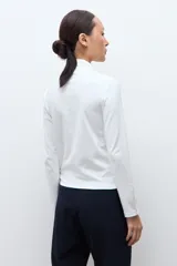 Media polera de manga larga con cuello alto y detalle de frunces en los puños, confeccionada en tejido suave y elástico.