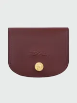 Tarjetero Longchamp de cuero color borravino, de formato semicircular con solapa frontal, grabado del logotipo del caballo y botón metálico dorado con detalles de la marca.