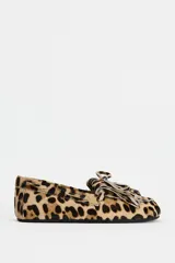 Mocasín plano de piel con pelo con estampado animal print, detalle de flecos y lazo en la parte delantera, pespuntes en contraste y punta redonda.
