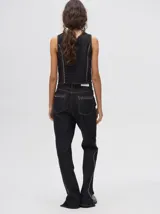 Pantalón de jean tiro alto con corte ochentoso y terminación oxford. Presenta apliques metálicos decorativos alrededor de los bolsillos delanteros y traseros, y a lo largo de la parte externa de las piernas.