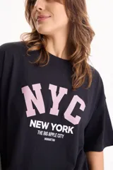 Remera de algodón negra de manga corta y corte holgado, con estampa frontal con la inscripción "NYC New York The Big Apple City".