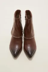 Bota corta de cuero color marrón con acabado degradado en la punta, tacón cuadrado y detalle de tachas metálicas plateadas en la parte superior del pie y el lateral.