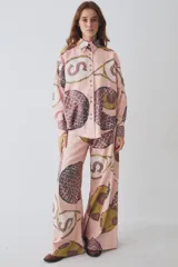 Pantalon de corte wide leg y tiro alto, confeccionado en tela con estampado deportivo que incluye pelotas de futbol y raquetas de tenis en tonos verde, rosa y beige.