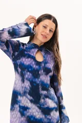 Vestido largo de manga larga con terminación campana, de color azul y violeta con estampado tie-dye, cuello mao con ojal y tajo frontal. Cuenta con flecos en el ruedo y tajo en la pierna.