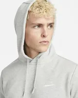 Hoodie Nike Sportswear Club Fleece gris melange, con capucha ajustable con cordones y bolsillo tipo canguro. Cuenta con el logotipo de la marca bordado en el pecho.