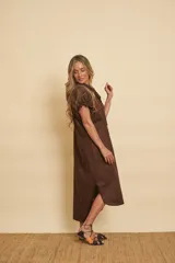 Vestido midi marrón de algodón, con mangas cortas abullonadas, cuello camisero y cierre frontal con botones y apliques metálicos dorados.