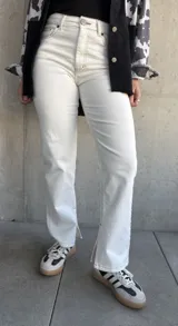 Pantalón de jean color natural, de corte recto con tajos en el lado interno de la pierna y costuras color oro.