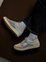 Zapatillas urbanas de diseño retro en tonos beige, marrón y celeste, confeccionadas en serraje con suela de goma color caramelo y cordones blancos.