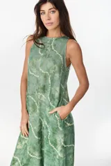 Vestido midi verde de lino italiano, con diseño sin mangas, cuello redondo y estampado de líneas onduladas punteadas. Cuenta con bolsillos laterales.