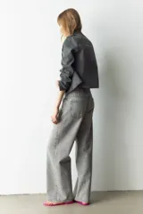 Jean de cinco bolsillos en denim de algodón rígido, de corte holgado estilo baggy, con piernas rectas y tiro alto. Presenta efecto deslavado y cierre con botón y cremallera.