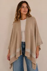 Ruana de tejido de algodón color beige, con detalle de franja calada en el borde inferior y terminaciones en rib.