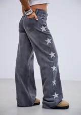 Jean de tiro medio en denim gris lavado, con corte recto y diseño de estrellas bordadas en color blanco a lo largo de los laterales externos de las piernas.