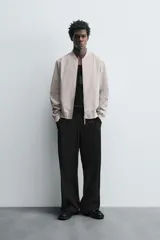 Cazadora bomber ligera de tejido técnico color verde oliva, con cuello, puños y bajo en rib elástico. Presenta cierre frontal de cremallera y bolsillos de vivo en la cadera.