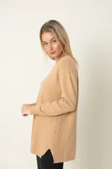 Buzo camel de viscosa y poliamida, con cuello redondo, corte holgado, tajos laterales y botones decorativos.