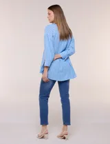 Blusa de silueta holgada a rayas verdes y blancas, confeccionada en tela liviana con textura arrugada. Presenta cuello en V profundo con botones frontales, mangas 3/4 de hombro caído y ruedo asimétrico con aberturas laterales.
