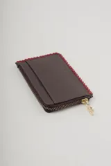 Billetera marrón de cuero sintético con cierre de cremallera y costuras rojas en los bordes.