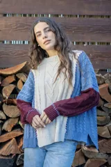 Sweater de punto con diseño de ochos y estilo patchwork, combinando paneles en colores terracota, marrón y beige. Presenta cuello redondo, mangas largas y costuras decorativas a la vista.