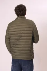 Chaqueta acolchada tipo puffer, color azul marino, con cuello alto y cierre frontal de cremallera.