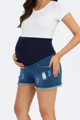 Short de jean de mezclilla azul con roturas y efecto gastado en el frente. Posee una faja de algodón elástica de color azul marino que cubre la zona del abdomen, ideal para maternidad. El ruedo es deshilachado.