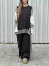 Conjunto de dos piezas en tejido de punto color beige, compuesto por un sweater de calce relajado con mangas a rayas y un pantalón de tiro alto con caída suelta y detalle lateral a rayas.