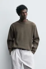 Jersey de punto con textura, corte relajado, cuello redondo y manga larga con acabados en rib.