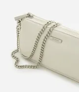 Cartera tipo baguette pequeña Satinato, confeccionada en PU color marfil, de formato alargado y estructura maleable. Cuenta con cierre superior de cremallera, placa frontal aplicada con el logo de la marca y asa de cadena doble metálica en tono plateado que permite llevarla al hombro o cruzada.