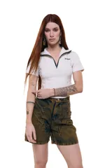 Top corto color crudo de gabardina elastizada, con cuello alto y cierre frontal con cremallera negra. Silueta entallada con recortes y costuras a contratono lila. Logo Temblad bordado en el pecho.