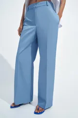 Pantalón de tiro medio con corte recto, confeccionado en mezcla de algodón. Presenta cintura con trabillas, bolsillos laterales ocultos en costura, raya planchada en el delantero y cierre frontal con cremallera, botón y ganchos metálicos.