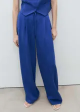 Pantalón de vestir de corte recto y tiro medio, confeccionado en tejido de lyocell. Presenta cierre delantero con cremallera, doble gancho y botón interior, además de trabillas y un cinturón tipo lazo en la cintura.