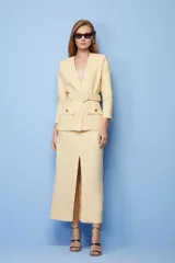 Falda midi color amarillo pálido, de corte recto con abertura frontal y cinturón con hebilla circular.