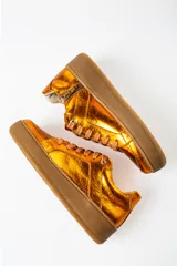 Zapatillas deportivas color naranja metalizado con cordones marrones y suela marrón.