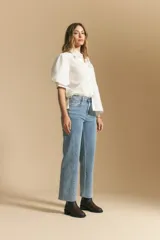 Jean de corte recto y tiro medio, confeccionado en denim elastizado de color negro. Presenta un diseño clásico con cierre de botón y cremallera, bolsillos laterales y traseros, y ruedo con terminación deshilachada.