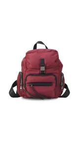 Mochila de nylon color bordó, con tapa superior y cierre de broche metálico. Presenta bolsillos frontales y laterales con cierres metálicos, correas ajustables para la espalda y asa de mano superior.