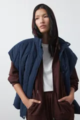 Chaleco acolchado de nylon con diseño capitoneado, cuello alto y cierre frontal con botones a presión. Presenta un calce amplio y versátil.