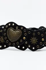 Cinturón negro de cuero sintético compuesto por una serie de piezas en forma de corazón unidas entre sí. Presenta detalles de tachas metálicas doradas y apliques decorativos en forma de sol, con un corazón central de mayor tamaño con diseño grabado.