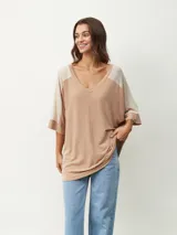 Remera oversize de manga corta con escote en V, de diseño bicolor en tonos beige y tostado, con mangas raglán y corte amplio.