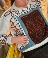 Sweater de lana merino color crudo, con cuello redondo y diseño geométrico tipo jacquard en el frente y las mangas.