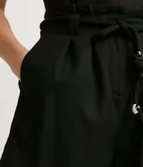 Short clochard de tiro alto con pliegues frontales, cintura con trabillas y cinturón de cuerda ajustable con detalle de cuentas. Confeccionado en tejido de viscolino con bolsillos laterales.