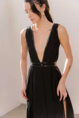 Vestido largo negro, con escote en V profundo ribeteado en ecuero y doble cinto del mismo material que marca la cintura. Cuenta con falda amplia con gran caída y aberturas laterales.