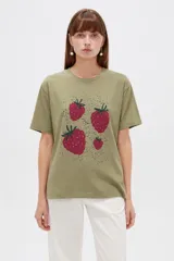Remera verde militar de algodón, de corte holgado y manga corta, con cuello redondo a la base y estampado frontal de fresas.