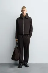 Pantalón regular fit color marrón oscuro, confeccionado en tejido con viscosa. Cuenta con cintura elástica, bolsillos delanteros y detalle de bolsillos traseros de vivo. El cierre frontal es con cremallera y botón.
