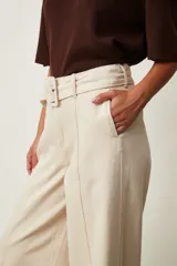 Jean azul oscuro de corte wide leg y tiro alto, con costuras pespunteadas verticales al frente y cinturón incorporado con hebilla cuadrada.